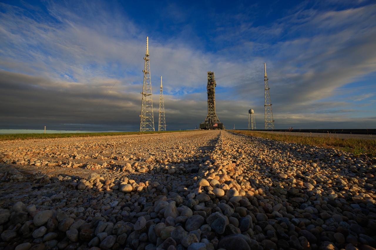 During sunrise on Oct. 30, 2020, the mobile launcher for the Artemis I mission, atop crawler-transporter 2, departs Launch Pad 39B and moves slowly along the crawlerway to return to the Vehicle Assembly Building at NASA’s Kennedy Space Center in Florida. The nearly 400-foot-tall mobile launcher was at the pad for 10 days, while engineers with Exploration Ground Systems and Jacobs performed several tasks, including a timing test to validate the launch team’s countdown timeline, and a thorough, top-to-bottom wash down of the mobile launcher to remove any debris remaining from construction and installation of the umbilical arms. Artemis I will test the Orion spacecraft and Space Launch System as an integrated system ahead of crewed flights to the Moon. Under the Artemis program, NASA will land the first woman and the next man on the Moon in 2024.