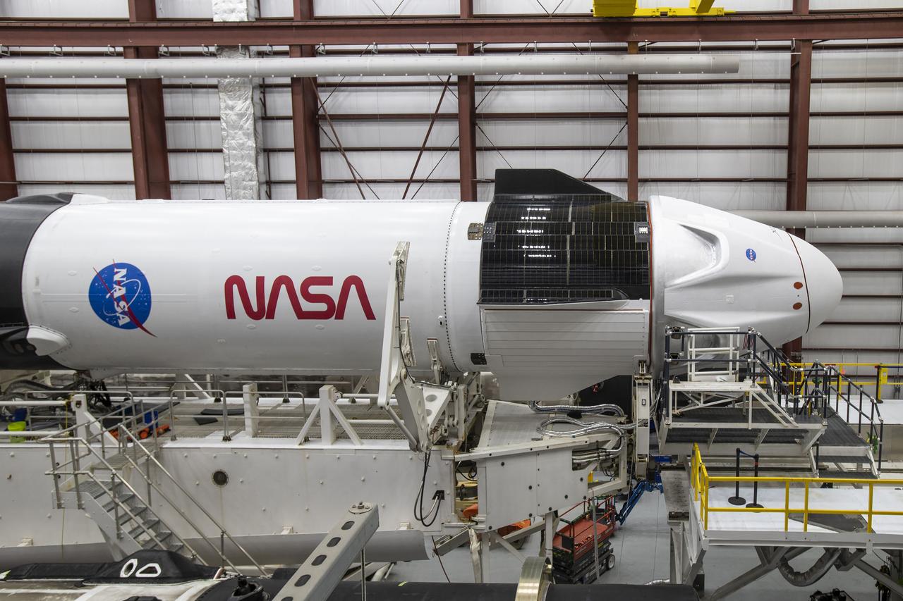 A SpaceX Falcon 9 rocket and Crew Dragon Resilience for NASA SpaceX’s Crew-1 mission are seen inside the SpaceX Hangar at NASA’s Kennedy Space Center in Florida on Nov. 9, 2020, before rollout to Launch Pad 39A. Crew-1 is the first regular crew mission of a U.S. commercial spacecraft with astronauts to the International Space Station as part of NASA’s Commercial Crew Program. The Crew Dragon capsule will launch atop a Falcon 9 rocket from Launch Complex 39A carrying NASA astronauts Michael Hopkins, Victor Glover, Shannon Walker and Japan Aerospace Exploration Agency (JAXA) astronaut Soichi Noguchi to the space station for a six-month science mission.