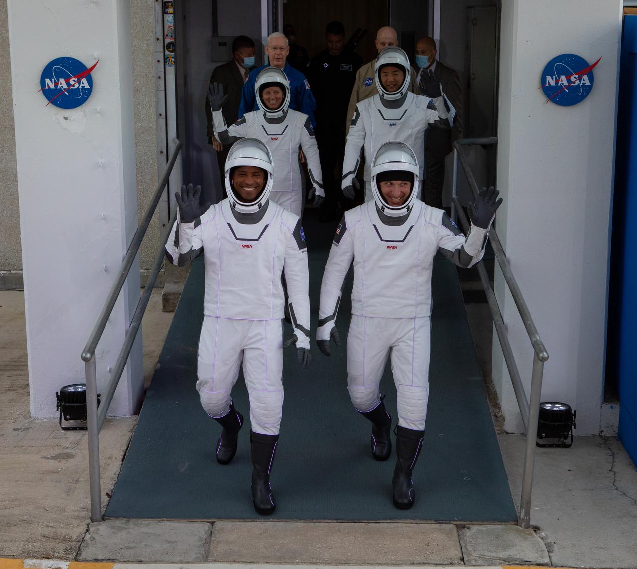 The NASA SpaceX Crew-1 astronauts emerge from the Neil Armstrong Operations and Checkout Building at NASA’s Kennedy Space Center in Florida on Nov. 15, 2020. In front, from left are NASA astronaut Victor Glover, pilot; and NASA astronaut Michael Hopkins, spacecraft commander. Behind them, from left are NASA astronaut Shannon Walker, mission specialist, and JAXA astronaut Soichi Noguchi, mission specialist. They will board two Tesla vehicles for the trip to Launch Complex 39A. Crew-1 is the first regular crew mission of a U.S. commercial spacecraft with astronauts to the International Space Station as part of NASA’s Commercial Crew Program. The SpaceX Crew Dragon Resilience capsule will launch atop the company’s Falcon 9 rocket from Pad 39A to the space station for a six-month science mission.