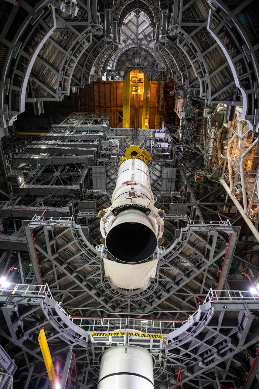 In a view looking up inside the Vehicle Assembly Building (VAB) at NASA’s Kennedy Space Center in Florida, the second of two Artemis I aft booster segments for the Space Launch System is lowered by crane into High Bay 3 on Nov. 24, 2020. Workers with Exploration Ground Systems and contractor Jacobs teams will stack the twin five-segment boosters on the mobile launcher in High Bay 3 over a number of weeks. When the core stage arrives, it will join the boosters on the mobile launcher, followed by the interim cryogenic propulsion stage and Orion spacecraft. Manufactured by Northrop Grumman in Utah, the twin boosters provide more than 75 percent of the total SLS thrust at launch. The SLS is managed by Marshall Space Flight Center in Huntsville, Alabama. Under the Artemis program, NASA will land the first woman and the next man on the Moon by 2024. The first in a series of increasingly complex missions, Artemis I will test the Orion spacecraft and SLS as an integrated system ahead of crewed flights to the Moon.