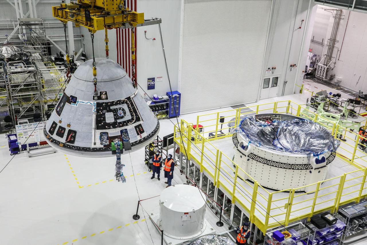 Boeing’s Starliner crew module is hoisted and moves past the service module in the Commercial Crew and Cargo Processing Facility at Kennedy Space Center in Florida on Wednesday, Jan. 13, 2021, prior to the weight and center of gravity test. The crew module and service module will soon be mated, making the spacecraft complete for the company’s second Orbital Flight Test (OFT-2) for NASA’s Commercial Crew Program. OFT-2 is a critical developmental milestone on the company’s path toward flying crew missions for NASA.