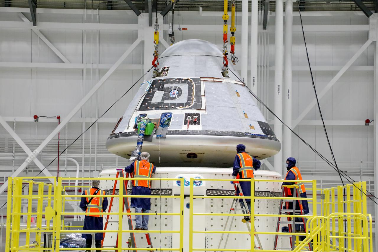 Technicians observe Boeing’s Starliner crew module being placed on top of the service module in the Commercial Crew and Cargo Processing Facility at NASA’s Kennedy Space Center in Florida on Jan. 14, 2021. The Starliner spacecraft is being prepared for Boeing’s second Orbital Flight Test (OFT-2). As part of the agency’s Commercial Crew Program, OFT-2 is a critical developmental milestone on the company’s path to fly crew missions for NASA.