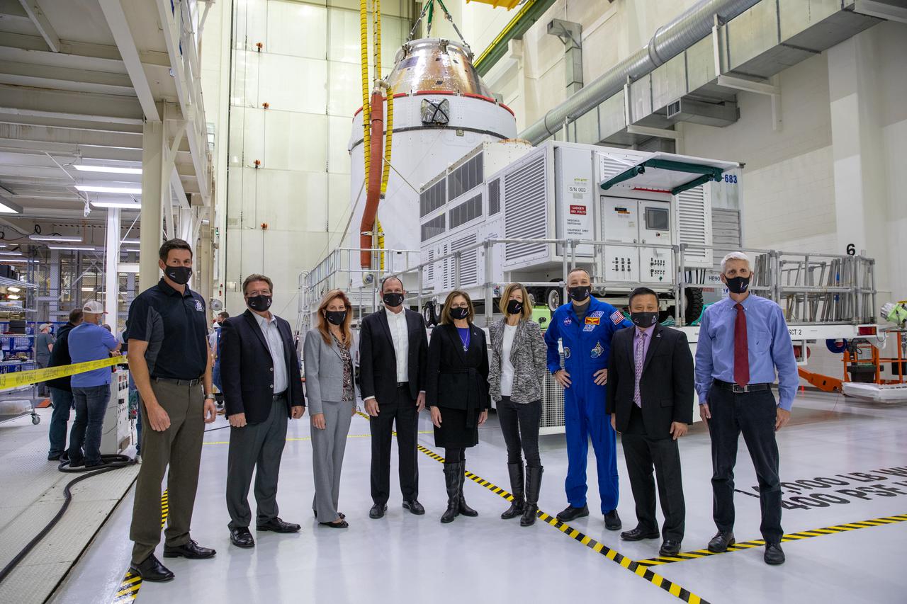 Orion is revealed for one of the final times on Jan. 14, as it is moved by crane to its transport pallet inside the Neil Armstrong Operations and Checkout Building at NASA’s Kennedy Space Center in Florida, along its path to the pad ahead of the Artemis I launch. Standing near Orion, from left, are Nathan Varn, Lockheed Martin Production Control director; Jules Schneider, Lockheed Martin Director of Orion Assembly, Test and Launch at Kennedy; Kelly DeFazio, Lockheed Martin Orion Program director for production operations; Tony Antonelli, Lockheed Martin Orion Program director and Artemis II mission director; Cathy Koerner, Orion Program manager; Kathy Lueders, associate administrator of the Human Exploration and Operations Mission Directorate; NASA astronaut Randy Bresnik; Howard Hu Orion Program deputy manager; and Scott Wilson, Orion Production Office manager. Teams across the globe have worked tirelessly to assemble the spacecraft, which will receive a protective covering prior to departing for the Multi-Payload Processing Facility to begin ground processing by the Exploration Ground Systems and Jacobs teams. 