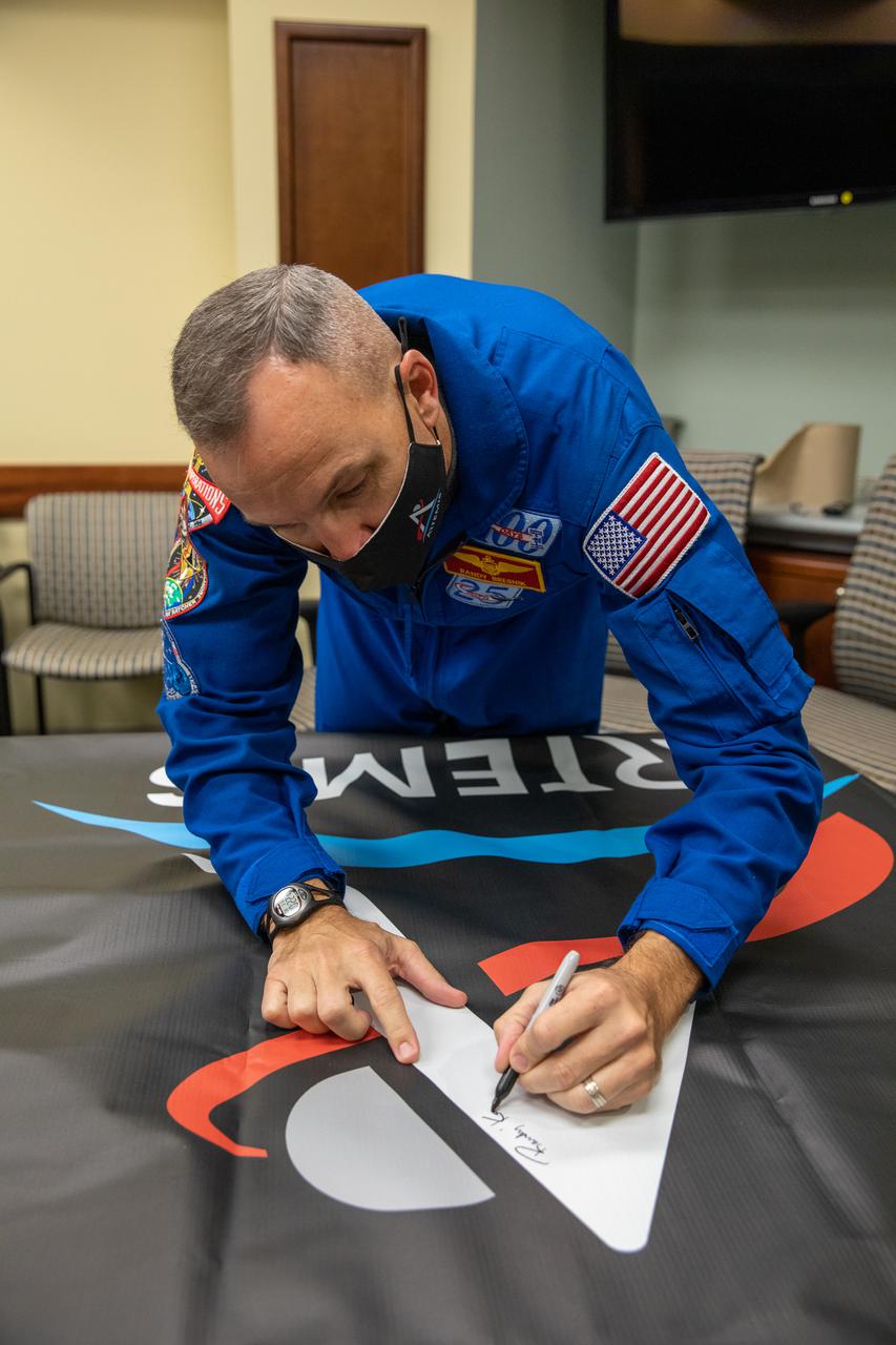 NASA astronaut Randy Bresnik signs an Artemis banner inside the Neil Armstrong Operations and Checkout Building at NASA’s Kennedy Space Center in Florida on Jan. 14, 2021. The banner will be hung on the KAMAG transporter ahead of the spacecraft’s journey to the Multi-Payload Processing Facility to begin ground processing by the Exploration Ground Systems and Jacobs teams.