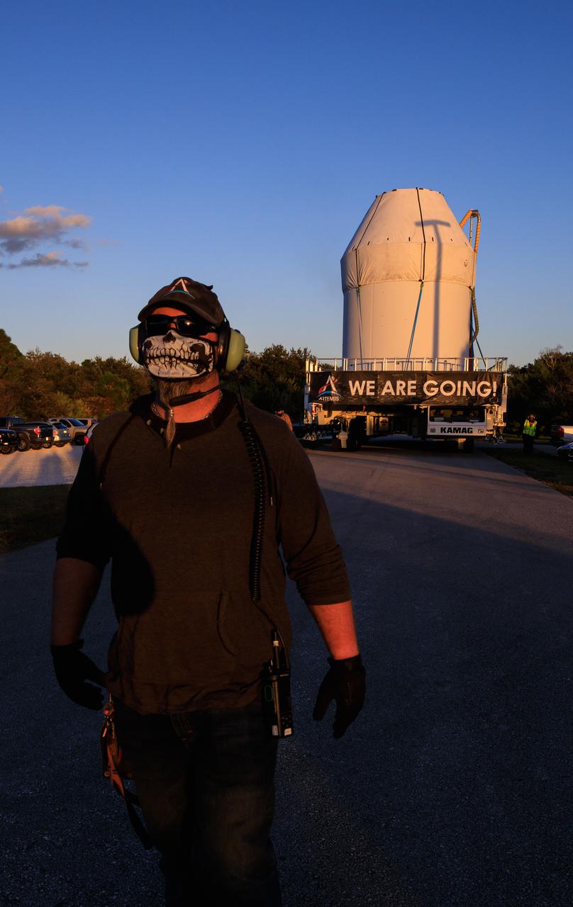 Secured atop a transport vehicle, Orion moves along the route to the Multi-Payload Processing Facility (MPPF) on Jan. 16, 2021, after departing from the Neil Armstrong Operations and Checkout Building at NASA’s Kennedy Space Center in Florida. Jason Parrish, a mechanical technician, Crawler Transporter Systems, with Jacobs, is one of the workers assisting with the move. Inside the MPPF, Orion will undergo processing with the Exploration Ground Systems team taking over ground processing ahead of the Artemis I launch.
