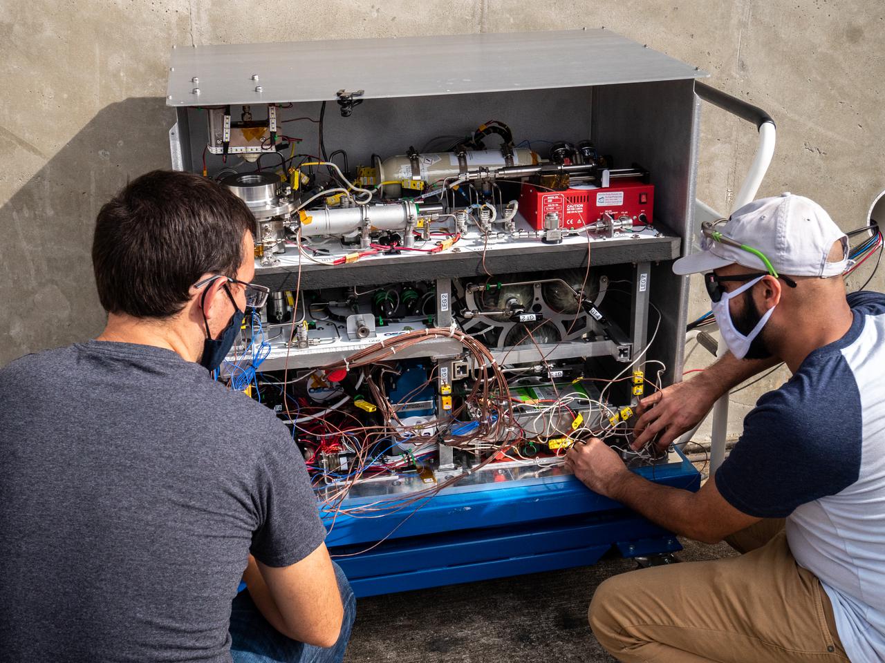 Chemical Engineer David Rinderknecht, left, and Thermal/Fluid Analysis Engineer Malay Shah prepare the Orbital Syngas Commodity Augmentation Reactor (OSCAR) for thermal testing Jan. 26, 2021, at NASA’s Kennedy Space Center in Florida. The tests are in preparation for a scheduled suborbital flight test later this year facilitated by NASA’s Flight Opportunities program. The testing ensures the thermal environment of the payload won’t create additional hazards during flight and that OSCAR can successfully operate within the temperature range it may encounter as it performs tests in microgravity.