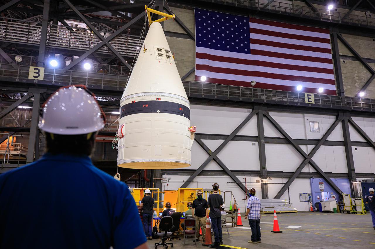 In the transfer aisle of the Vehicle Assembly Building at NASA’s Kennedy Space Center in Florida, workers use a crane to lift up the left-hand booster forward assembly for the agency’s Space Launch System for transfer into High Bay 3 on March 1, 2021. The forward assembly will be attached to the center forward segment on the mobile launcher (ML). Exploration Ground Systems and contractor Jacobs teams have been stacking the twin five-segment boosters on the ML over a number of weeks. When the core stage arrives, it will join the boosters on the mobile launcher, followed by the interim cryogenic propulsion stage and Orion spacecraft. Manufactured by Northrop Grumman in Utah, the twin boosters provide more than 75 percent of the total SLS thrust at launch. Marshall Space Flight Center in Huntsville, Alabama, manages the SLS. Under the Artemis program, NASA will land the first woman and the next man on the Moon. The first in a series of increasingly complex missions, Artemis I will test the Orion spacecraft and SLS as an integrated system ahead of crewed flights to the Moon.