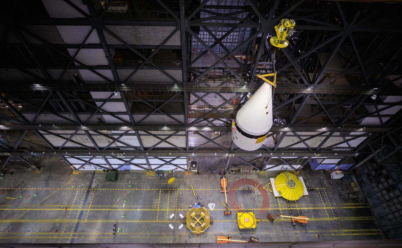 This view from high up in the Vehicle Assembly Building at NASA Kennedy Space Center in Florida, shows a crane lifting the left-hand forward assembly for NASA’s Space Launch System (SLS) in the transfer aisle on March 1, 2021. Workers are lifting the segment up for transfer into High Bay 3, where it will be attached to the center forward segment on the mobile launcher (ML). Exploration Ground Systems and contractor Jacobs teams have been stacking the twin five-segment boosters on the ML over a number of weeks. When the core stage arrives, it will join the boosters on the mobile launcher, followed by the interim cryogenic propulsion stage and Orion spacecraft. Manufactured by Northrop Grumman in Utah, the twin boosters provide more than 75 percent of the total SLS thrust at launch. Marshall Space Flight Center in Huntsville, Alabama, manages the SLS. Under the Artemis program, NASA will land the first woman and the next man on the Moon. The first in a series of increasingly complex missions, Artemis I will test the Orion spacecraft and SLS as an integrated system ahead of crewed flights to the Moon.