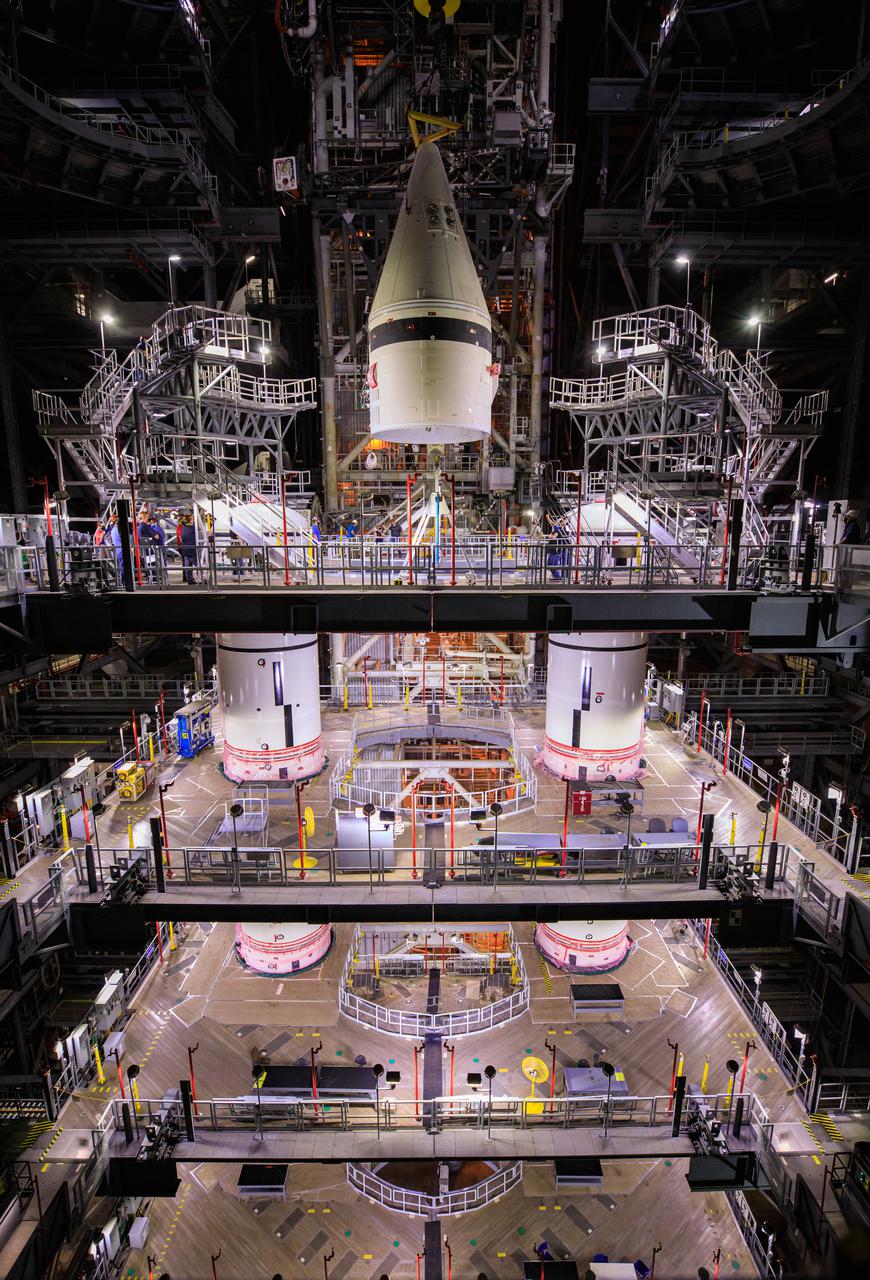The left-hand booster forward assembly for NASA’s Space Launch System is lowered by crane onto the center forward segment on the mobile launcher (ML) in High Bay 3 of the Vehicle Assembly Building at Kennedy Space Center in Florida on March 1, 2021. Exploration Ground Systems and contractor Jacobs teams have been stacking the twin five-segment boosters on the ML over a number of weeks. When the core stage arrives, it will join the boosters on the mobile launcher, followed by the interim cryogenic propulsion stage and Orion spacecraft. Manufactured by Northrop Grumman in Utah, the twin boosters provide more than 75 percent of the total SLS thrust at launch. Marshall Space Flight Center in Huntsville, Alabama, manages the SLS. Under the Artemis program, NASA will land the first woman and the next man on the Moon. The first in a series of increasingly complex missions, Artemis I will test the Orion spacecraft and SLS as an integrated system ahead of crewed flights to the Moon.