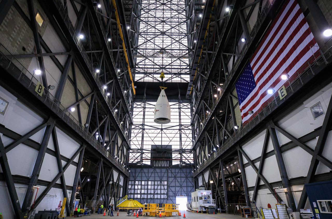 In the transfer aisle of the Vehicle Assembly Building at NASA’s Kennedy Space Center in Florida, workers use a crane to lift the right-hand forward assembly for the Space Launch System (SLS) high up for transfer into High Bay 3 on March 2, 2021. The forward assembly will be attached to the center forward segment on the mobile launcher (ML). Workers with Exploration Ground Systems and contractor Jacobs teams are stacking the twin five-segment boosters on the ML over a number of weeks. When the core stage arrives, it will join the boosters on the mobile launcher, followed by the interim cryogenic propulsion stage and Orion spacecraft. Manufactured by Northrop Grumman in Utah, the twin boosters provide more than 75 percent of the total SLS thrust at launch. Marshall Space Flight Center in Huntsville, Alabama, manages the SLS. Under the Artemis program, NASA will land the first woman and the next man on the Moon. The first in a series of increasingly complex missions, Artemis I will test the Orion spacecraft and SLS as an integrated system ahead of crewed flights to the Moon.