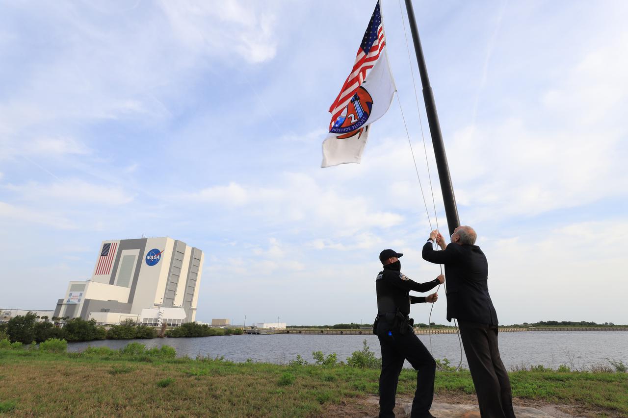 NASA acting administrator Steve Jurczyk raises the Crew-2 flag near the countdown clock at Kennedy Space Center’s Press Site on April 24, 2021. In the background is the Florida spaceport’s Vehicle Assembly Building. NASA’s SpaceX Crew-2 mission launched NASA astronaut Shane Kimbrough, spacecraft commander; NASA astronaut Megan McArthur, pilot; ESA astronaut Thomas Pesquet, mission specialist; and JAXA astronaut Akihiko Hoshide, mission specialist, to the International Space Station on April 23. Liftoff, from Kennedy’s Launch Complex 39A, was at 5:49 a.m. EDT. The SpaceX Crew Dragon Endeavour docked to the space station on April 24, at 5:08 a.m. EDT.