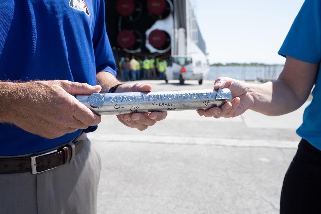 The Space Launch System (SLS) program heralds the arrival of the SLS core stage with a symbolic “passing of the baton” to NASA’s Exploration Ground Systems (EGS) on April 28, 2021, at the agency’s Kennedy Space Center in Florida, marking the transition into final preparations for flight. Journeying from NASA’s Stennis Space Center in Mississippi aboard the Pegasus barge, the core stage arrived at the Florida spaceport on April 27. It is the final piece of Artemis hardware to arrive at Kennedy and will be offloaded and moved to the Vehicle Assembly Building, where it will be prepared for integration atop the mobile launcher with the completed stack of solid rocket boosters ahead of the Artemis I launch. The first in a series of increasingly complex missions, Artemis I will test SLS and Orion as an integrated system prior to crewed flights to the Moon.