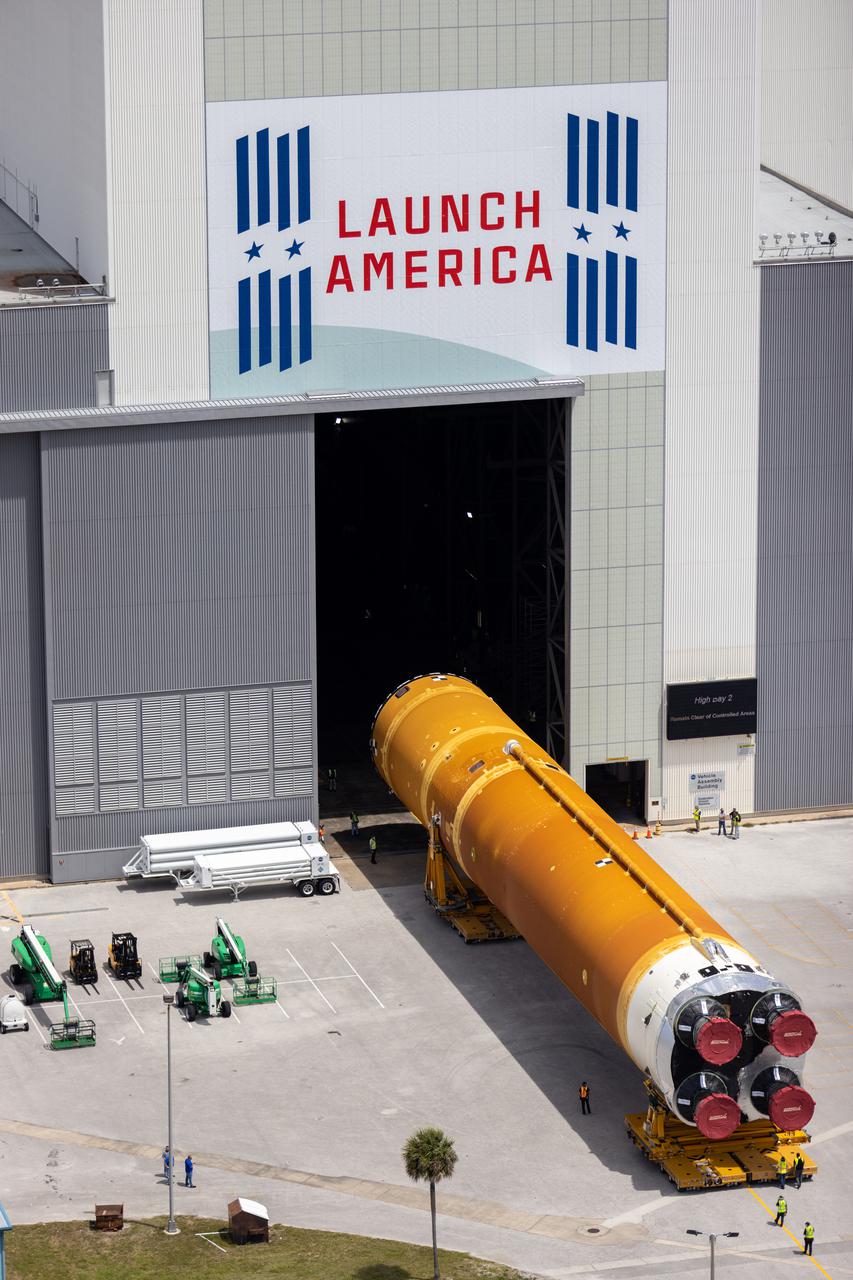After completing its journey from NASA’s Stennis Space Center in Mississippi aboard the Pegasus barge, teams with Exploration Ground Systems (EGS) and lead contractor Jacobs transport the massive Space Launch System (SLS) core stage to Kennedy Space Center’s Vehicle Assembly Building in Florida on April 29, 2021 in this aerial view. Once inside the VAB, it will be prepared for integration with the completed stack of solid rocket boosters atop the mobile launcher ahead of the Artemis I launch. The first in a series of increasingly complex missions, Artemis I will test SLS and Orion as an integrated system prior to crewed flights to the Moon.