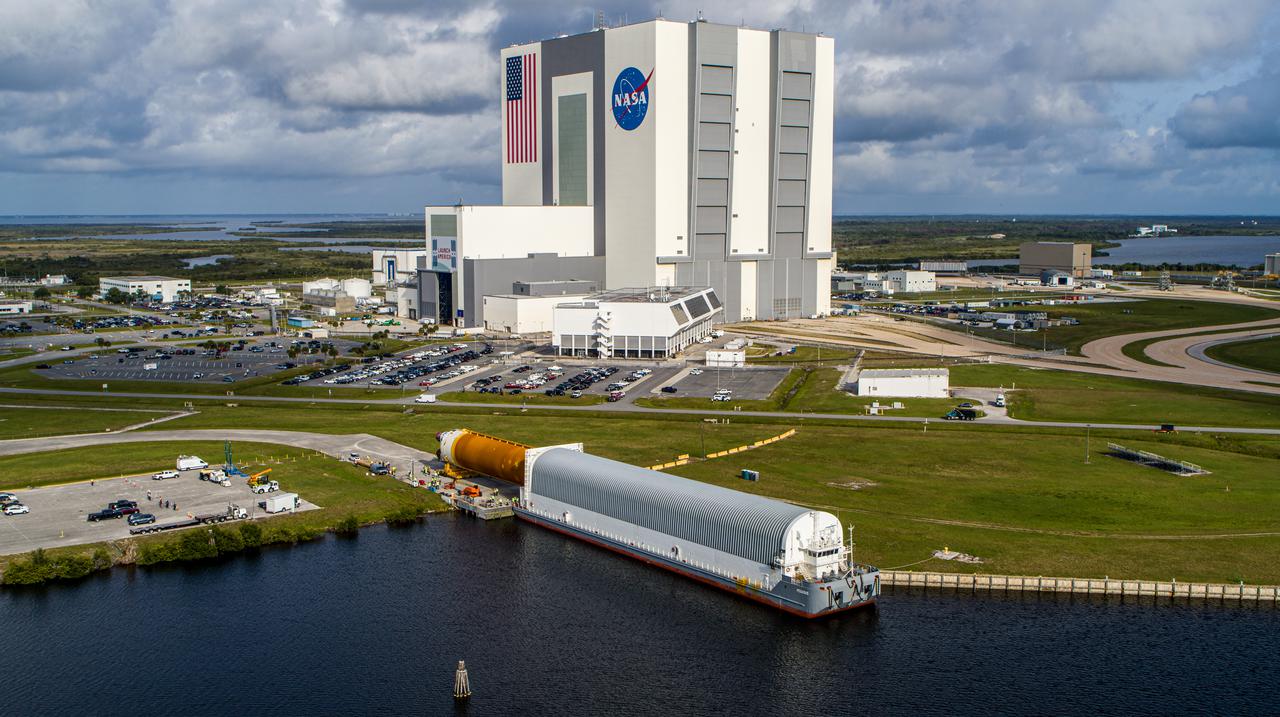 In this aerial view, the massive 212-foot long Space Launch System (SLS) core stage is shown being offloaded from the Pegasus Barge on April 29, 2021, after arriving at NASA’s Kennedy Space Center in Florida. Teams with Exploration Ground Systems (EGS) and lead contractor Jacobs will transfer the rocket stage to the center’s Vehicle Assembly Building to prepare it for integration with the completed stack of solid rocket boosters atop the mobile launcher ahead of the Artemis I launch. The first in a series of increasingly complex missions, Artemis I will test SLS and Orion as an integrated system prior to crewed flights to the Moon.