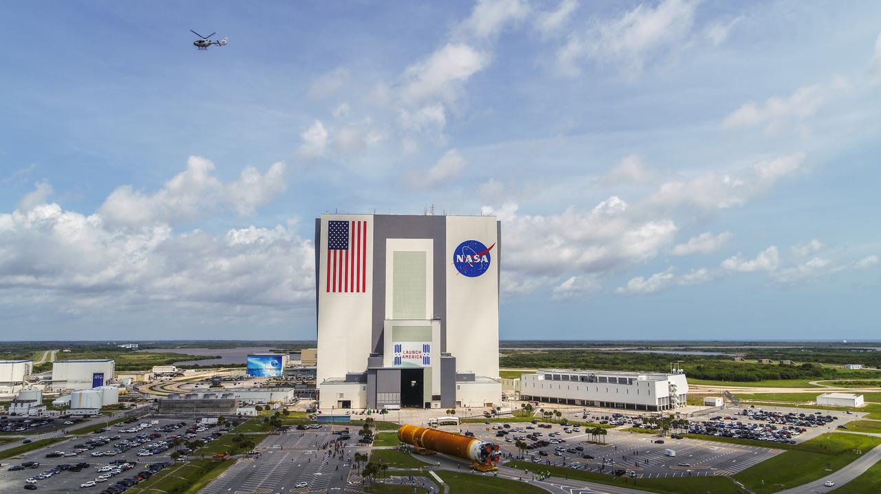 After completing its journey from NASA’s Stennis Space Center in Mississippi aboard the Pegasus barge, teams with Exploration Ground Systems (EGS) and lead contractor Jacobs transport the massive Space Launch System (SLS) core stage to Kennedy Space Center’s Vehicle Assembly Building in Florida on April 29, 2021 in this aerial view. A NASA helicopter is in view in the upper left of the photograph. Once inside the VAB, the core stage will be prepared for integration with the completed stack of solid rocket boosters atop the mobile launcher ahead of the Artemis I launch. The first in a series of increasingly complex missions, Artemis I will test SLS and Orion as an integrated system prior to crewed flights to the Moon.