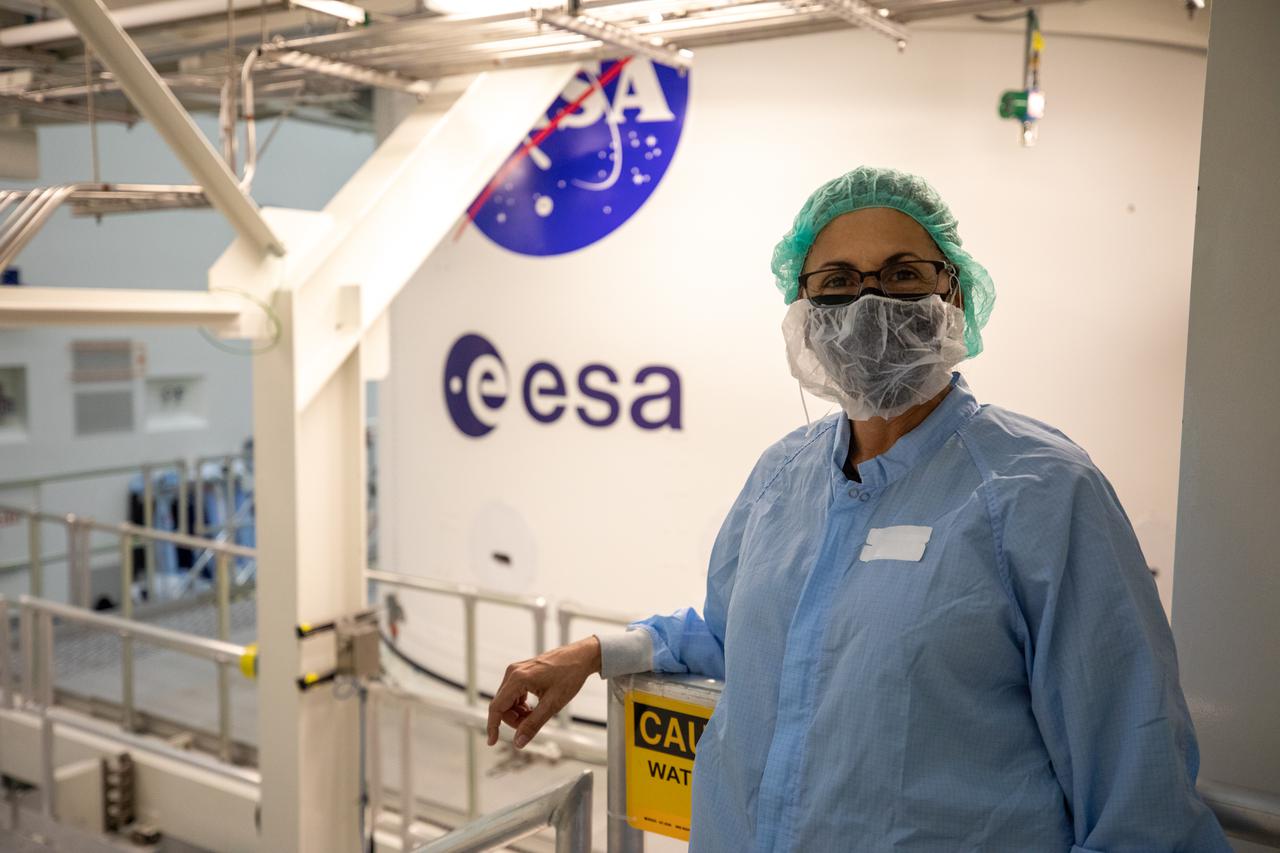 Nicole Stott, NASA Astronaut (former), shown next to the NASA “meatball” and European Space Agency insignias on the European-built service module for the Orion spacecraft, inside the Multi-Payload Processing Facility (MPPF) during a visit to NASA’s Kennedy Space Center in Florida on May 10, 2021. The first in a series of increasingly complex missions, Artemis I will test Orion and the Space Launch System rocket as an integrated system prior to crewed flights to the Moon.