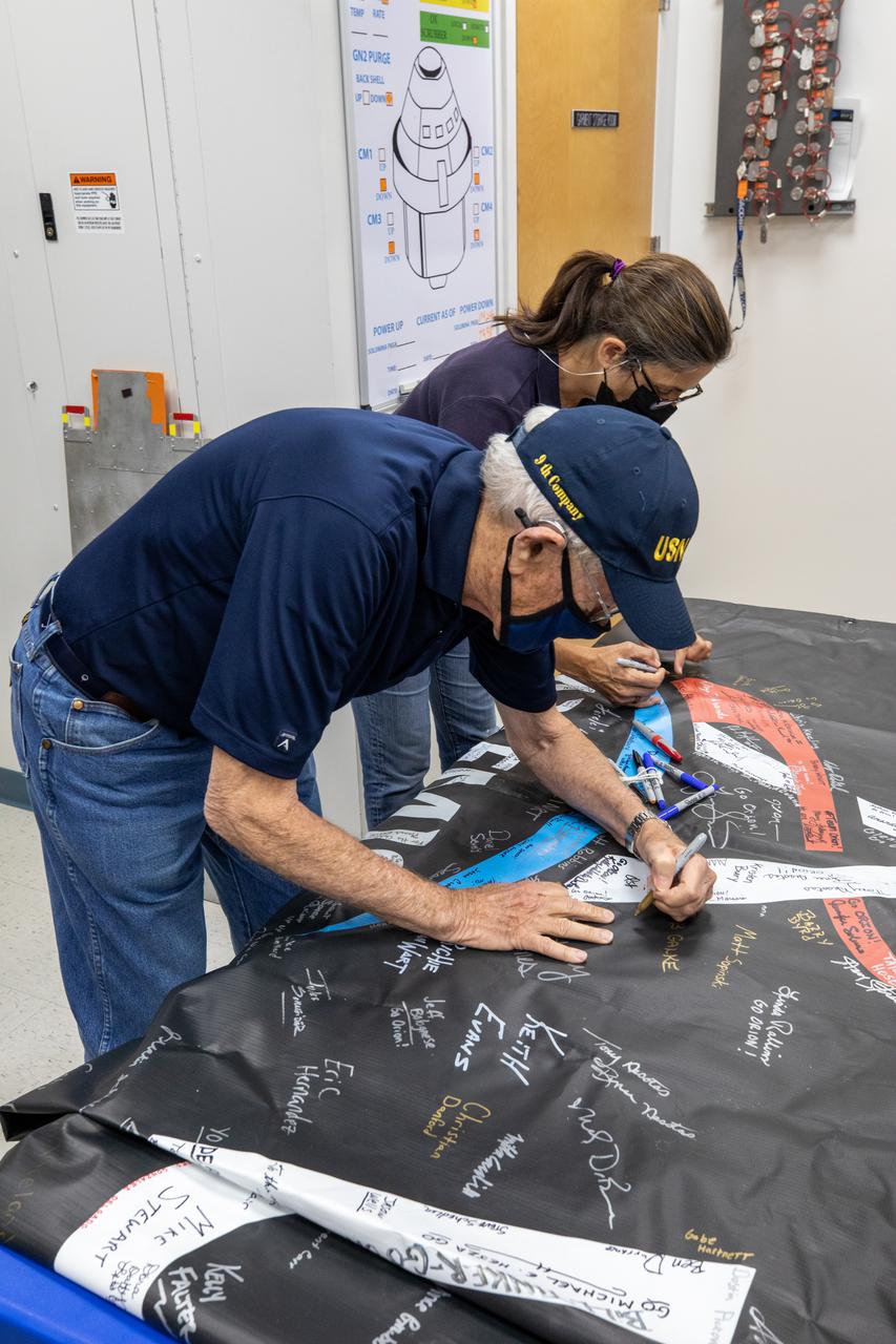 Charlie Duke, NASA Astronaut (former), and Nicole Stott, NASA Astronaut (former), add their signatures to the Artemis “We Are Going” banner inside the Multi-Payload Processing Facility (MPPF) during a visit to NASA’s Kennedy Space Center in Florida on May 10, 2021. During their time at Kennedy, they also had the opportunity to view the Orion spacecraft  and  Interim Cryogenic Propulsion Stage currently being serviced inside the MPPF ahead of the Artemis I launch. The first in a series of increasingly complex missions, Artemis I will test Orion and the Space Launch System rocket as an integrated system prior to crewed flights to the Moon.