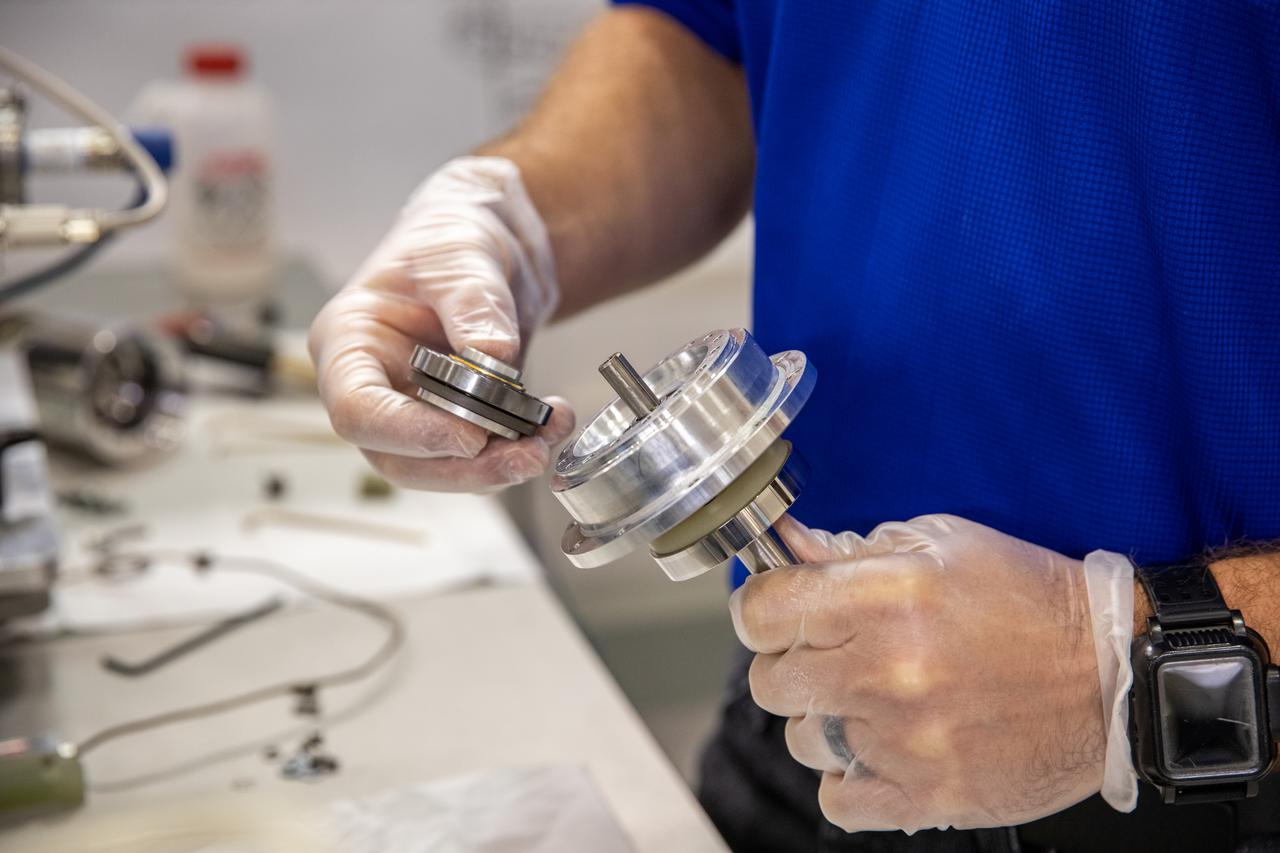 Drew Smith, a robotics engineer and lab manager with the Exploration Research and Technology programs at NASA's Kennedy Space Center, prepares a Bulk Metallic Glass Gear (BMGG) for ambient temperature tests in a vacuum inside a cryogenic cooler at Kennedy's Granular Mechanics and Regolith Operations lab on June 17, 2021. Made from a custom bulk metallic glass alloy, BMGGs could be used in heater-free gearboxes at extremely low temperatures in locations such as the Moon, Mars, and Europa, one of Jupiter’s moons. NASA’s Jet Propulsion Laboratory is working with commercial partners to create the gears.