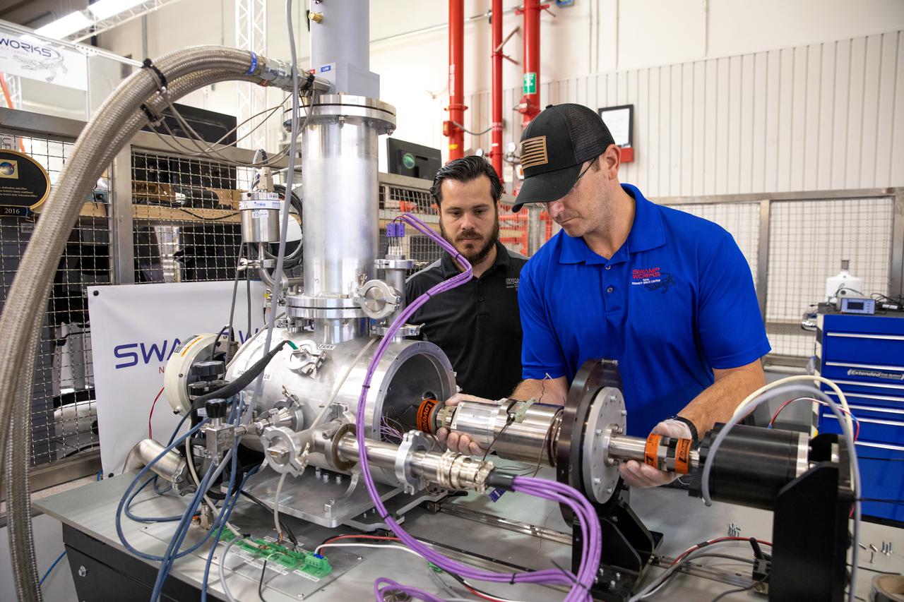 A.J. Nick, left, and Drew Smith, robotics engineers with the Exploration Research and Technology programs at NASA's Kennedy Space Center, test Bulk Metallic Glass Gears (BMGGs) in a vacuum inside a cryogenic cooler at Kennedy's Granular Mechanics and Regolith Operations lab on June 17, 2021. Made from a custom bulk metallic glass alloy, BMGGs could be used in heater-free gearboxes at extremely low temperatures in locations such as the Moon, Mars, and Europa, one of Jupiter’s moons. NASA’s Jet Propulsion Laboratory is working with commercial partners to create the gears.