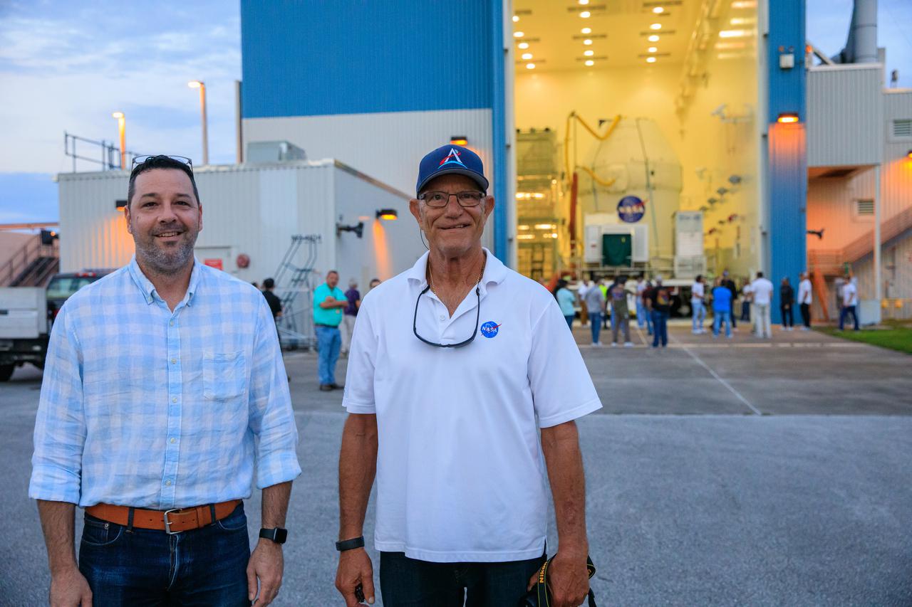 Mike Collins, NASA Operations manager for Spacecraft Offline Operations, left, and Skip Williams, operations manager for the Multi-Payload Processing Facility (MPPF) spacecraft offline element integration team, stand in front of the Orion spacecraft for the Artemis I mission, as the capsule moves out from Kennedy Space Center’s MFFP on July 10, 2021. Orion is being transported to the Florida spaceport’s Launch Abort System Facility, where teams with Exploration Ground Systems and contractor Jacobs will integrate components of the launch abort system onto the spacecraft. Launching later this year, Artemis I will be a test of the Orion spacecraft and SLS rocket as an integrated system ahead of crewed flights to the Moon.