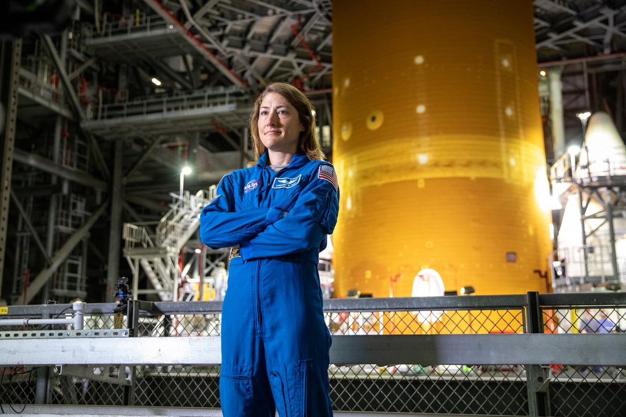 NASA astronaut Christina Koch stands inside Kennedy Space Center’s Vehicle Assembly Building on July 14, 2021, in front of the agency’s Space Launch System (SLS) rocket that will power the Orion spacecraft on the Artemis I mission later this year. Artemis I will be an uncrewed flight test of Orion and SLS as an integrated system ahead of missions with astronauts. Under Artemis, NASA aims to land the first woman and first person of color on the Moon and establish a long-lasting presence on and around the Moon while preparing for human missions to Mars.
