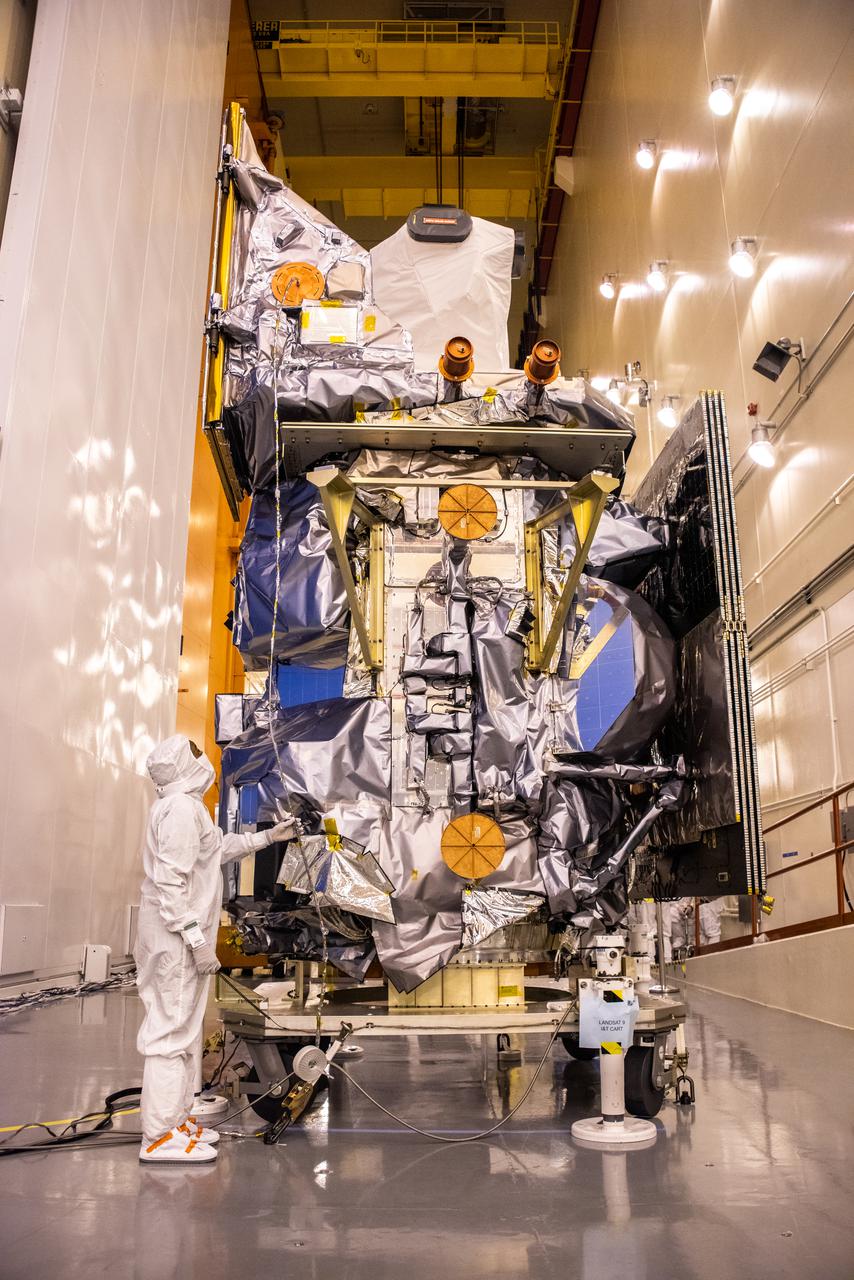 Inside the Integrated Processing Facility at Vandenberg Space Force Base in California, technicians begin to remove the protective cover from NASA’s Landsat 9 observatory on July 14, 2021. Landsat 9 will launch on a United Launch Alliance Atlas V rocket from Space Launch Complex 3 at Vandenberg in September 2021. The launch is being managed by NASA’s Launch Services Program based at Kennedy Space Center, America’s multiuser spaceport. The Landsat 9 satellite will continue the nearly 50-year legacy of previous Landsat missions. It will monitor key natural and economic resources from orbit. The satellite will carry two instruments: the Operational Land Imager 2, which collects images of Earth’s landscapes in visible, near infrared and shortwave infrared light, and the Thermal Infrared Sensor 2, which measures the temperature of land surfaces. Like its predecessors, Landsat 9 is a joint mission between NASA and the U.S. Geological Survey. Landsat 9 is managed by the agency’s Goddard Space Flight Center in Greenbelt, Maryland.