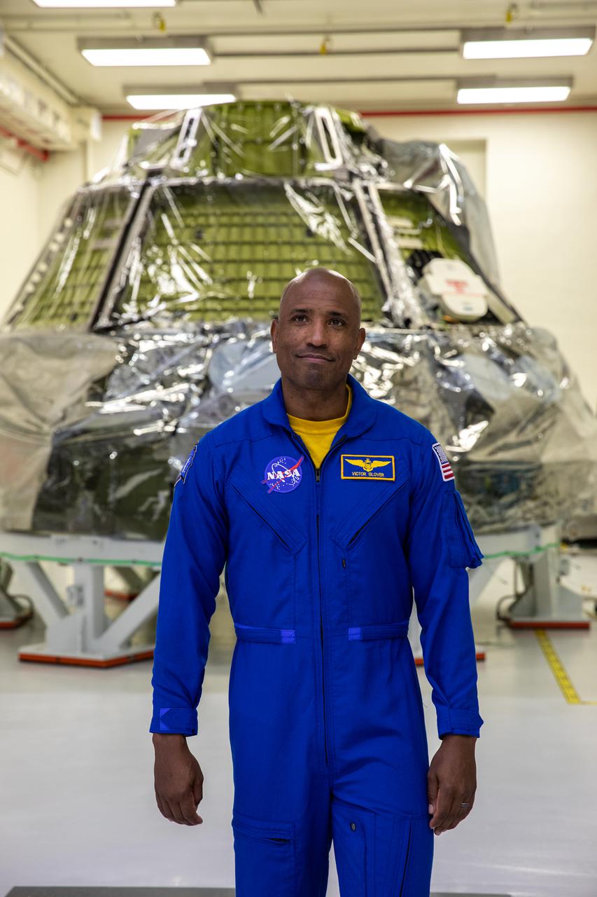NASA astronaut Victor Glover stands inside Kennedy Space Center’s Neil A. Armstrong Operations and Checkout Building on July 15, 2021, near the crew module for the agency’s Artemis II mission. Artemis will lay the foundation for a sustained long-term presence on the lunar surface. NASA will use the Moon to validate deep space systems and operations before embarking on a human voyage to Mars.