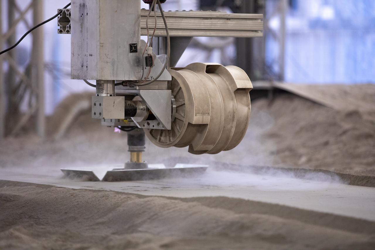 A team at NASA’s Kennedy Space Center in Florida tests small- and medium-sized bucket drums July 16, 2021, in the Granular Mechanics and Regolith Operations Lab’s “big bin” during prototype development for the pilot excavator, a robotic mission designed for lunar operations. The bucket drum excavated lunar regolith simulant. The Swamp Works team leveled and compacted the simulant before excavation as well as measured penetration during the excavator testing. Robotics engineers Jason Schuler and Austin Langton worked inside the bin, teaming up with software engineer Kurt Leucht, who worked just outside of it.