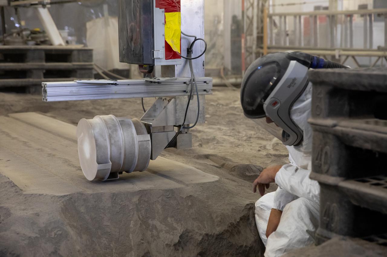 A team at NASA’s Kennedy Space Center in Florida tests small- and medium-sized bucket drums July 16, 2021, in the Granular Mechanics and Regolith Operations Lab’s “big bin” during prototype development for the pilot excavator, a robotic mission designed for lunar operations. The bucket drum excavated lunar regolith simulant. The Swamp Works team leveled and compacted the simulant before excavation as well as measured penetration during the excavator testing. Robotics engineers Jason Schuler and Austin Langton worked inside the bin, teaming up with software engineer Kurt Leucht, who worked just outside of it.