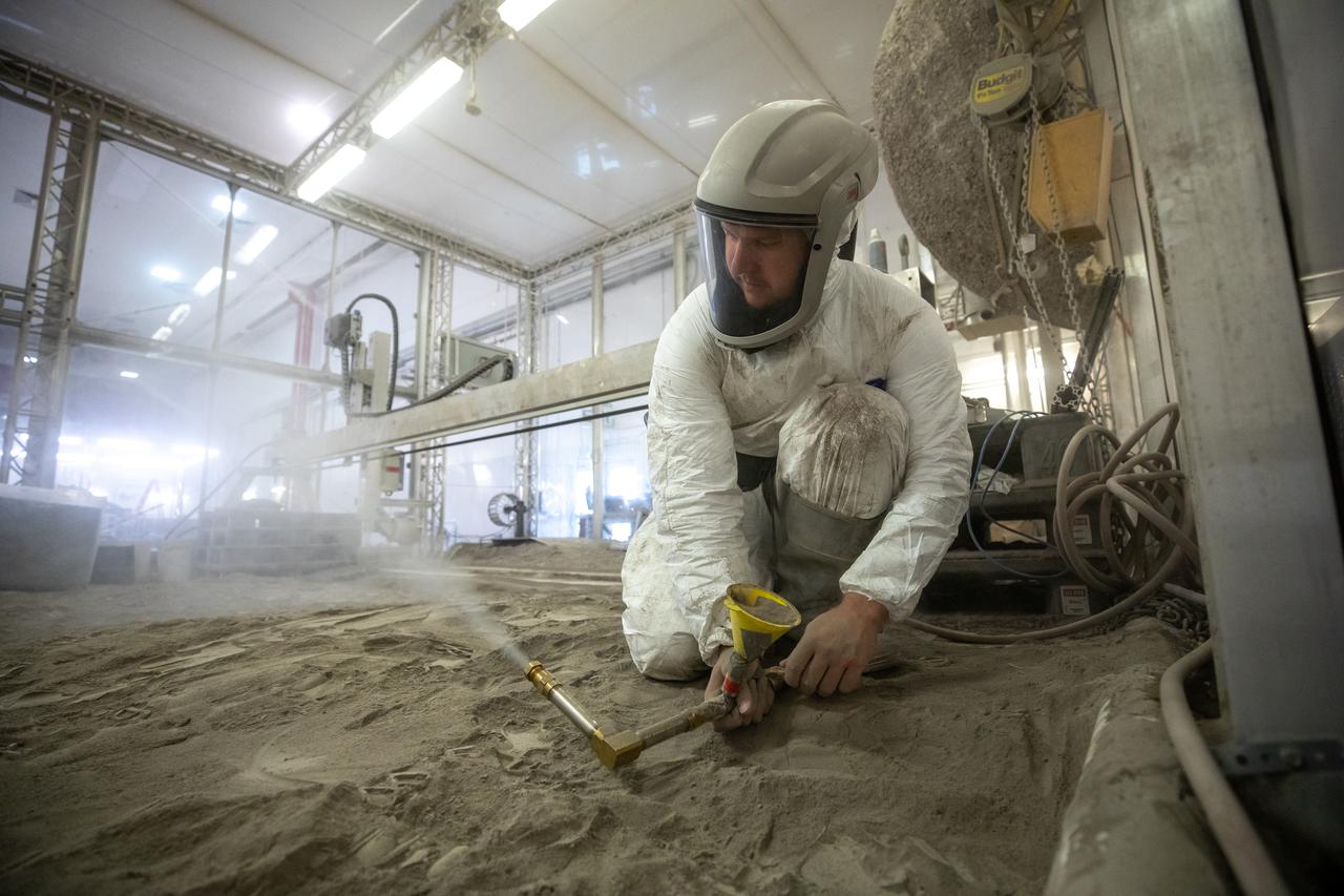 Austin Langton, a researcher at NASA's Kennedy Space Center in Florida, creates a fine spray of the regolith simulant BP-1, to perform testing with a Millimeter Wave Doppler Radar at the Granular Mechanics and Regolith Operations Lab on July 16, 2021. The testing occurred inside the "Big Bin," an enclosure at Swamp Works that holds 120 tons of regolith simulant. The testing at the Florida spaceport is part of a project to predict plume surface interaction effects on the Moon, with testing happening at Kennedy, and NASA's Marshal Space Flight Center and Glenn Research Center.