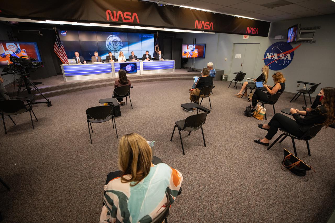 Members of the media gather in the Kennedy Space Center’s Press Site auditorium in Florida during a prelaunch news conference with NASA, Boeing, United Launch Alliance (ULA) and the U.S. Space Force 45th Weather Squadron officials, July 27, 2021, prior to the Friday, July 30, launch of NASA’s Boeing Orbital Flight Test-2 (OFT-2).  . From left to right at the dais are Kyle Herring, NASA Communications; Steve Stich, manager, NASA’s Commercial Crew Program; Joel Montalbano, manager, NASA’s International Space Station Program; Jennifer Buchli, deputy chief scientist, NASA’s International Space Station Program; John Vollmer, vice president and program manager, Boeing Commercial Crew Program; Gary Wentz, vice president, Government and Commercial Programs, ULA; Will Ulrich, launch weather officer, U.S. Space Force, 45th Weather Squadron. Boeing’s CST-100 Starliner spacecraft will launch atop a ULA Atlas V rocket from Space Launch Complex-41 at Cape Canaveral Space Force Station on a mission to dock with the space station. The uncrewed OFT-2 will be the Starliner’s second flight for NASA’s Commercial Crew Program. 