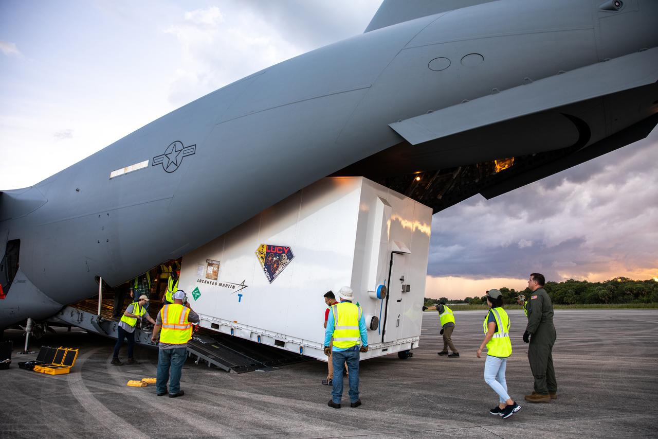 The shipping container holding NASA's Lucy spacecraft is unloaded from a United States Air Force C-17 cargo plane, stationed out of Charleston Air Force Base in South Carolina, on the runway of the Launch and Landing Facility at Kennedy Space Center in Florida on July 30, 2021. From there, the Lucy spacecraft will move to the Astrotech Space Operations payload processing facility in nearby Titusville, Florida, before its scheduled launch on a United Launch Alliance (ULA) Atlas V rocket from Cape Canaveral Space Force Station on October 16, 2021. The Lucy mission will be the first space mission to explore a diverse population of small bodies known as the Jupiter Trojan asteroids. The launch is being managed by NASA's Launch Services Program based at Kennedy, America's multi-user spaceport. 
