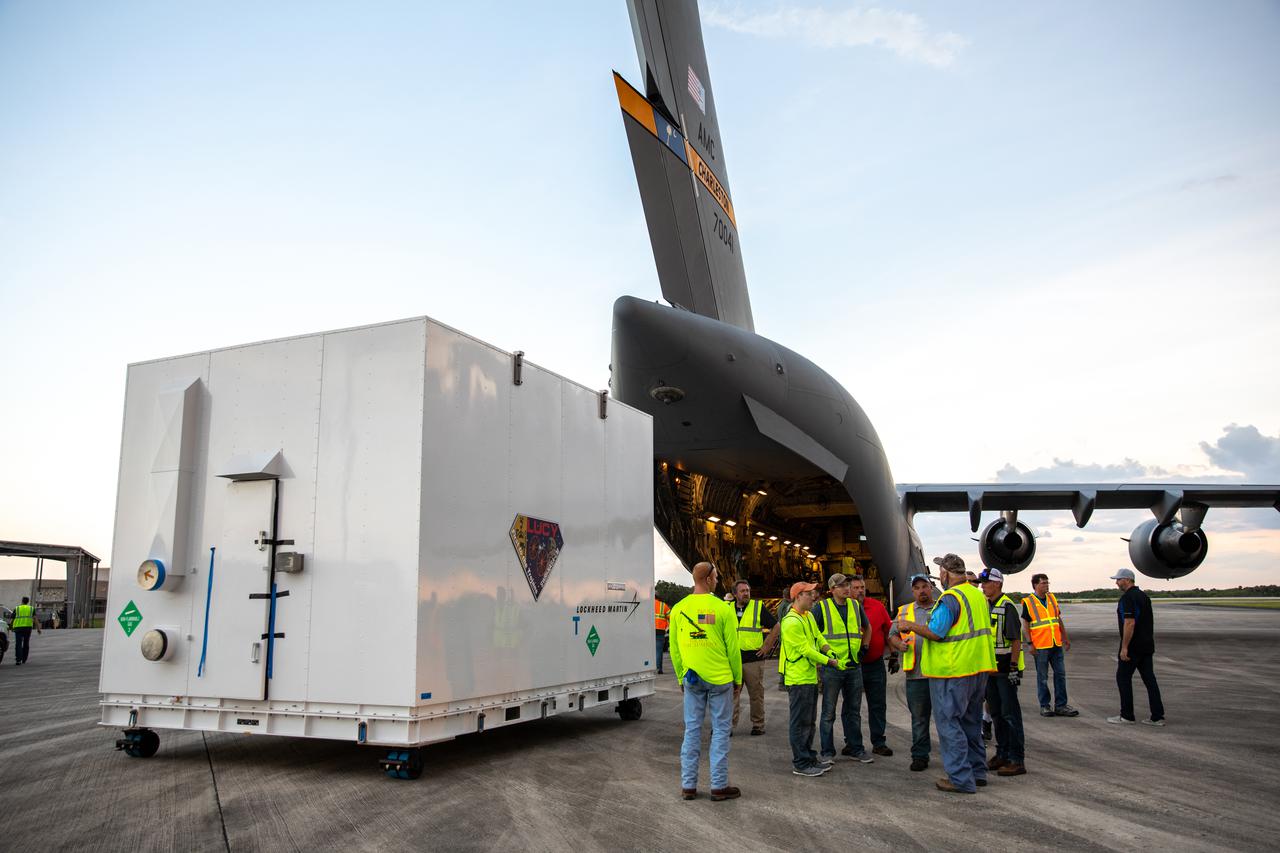 The shipping container holding NASA's Lucy spacecraft is unloaded from an Air Force C-17 cargo aircraft on the runway of the Launch and Landing Facility at Kennedy Space Center in Florida on July 30, 2021. From there, the Lucy spacecraft will move to the Astrotech Space Operations payload processing facility in nearby Titusville, Florida, before its scheduled launch on a United Launch Alliance (ULA) Atlas V rocket from Cape Canaveral Space Force Station on October 16, 2021. The Lucy mission will be the first space mission to explore a diverse population of small bodies known as the Jupiter Trojan asteroids. The launch is being managed by NASA's Launch Services Program based at Kennedy, America's premier multi-user spaceport. 