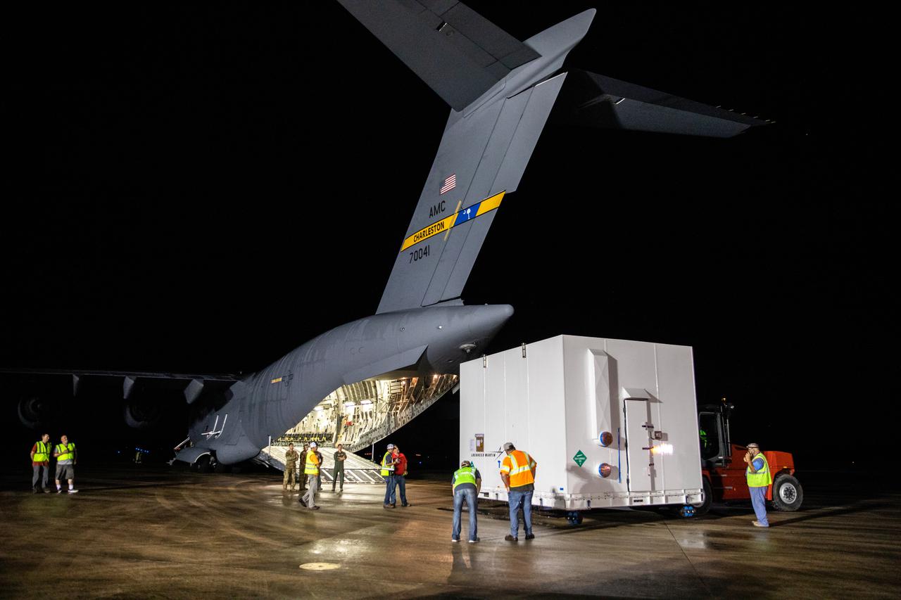 The shipping container holding NASA's Lucy spacecraft is unloaded from a United States Air Force C-17 cargo plane, stationed out of Charleston Air Force Base in South Carolina, on the runway of the Launch and Landing Facility at Kennedy Space Center in Florida on July 30, 2021. From there, the Lucy spacecraft will move to the Astrotech Space Operations payload processing facility in nearby Titusville, Florida, before its scheduled launch on a United Launch Alliance (ULA) Atlas V rocket from Cape Canaveral Space Force Station on October 16, 2021. The Lucy mission will be the first space mission to explore a diverse population of small bodies known as the Jupiter Trojan asteroids. The launch is being managed by NASA's Launch Services Program based at Kennedy, America's multi-user spaceport. 