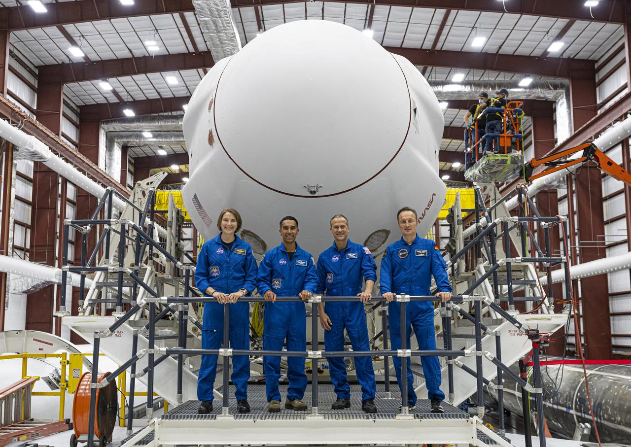 The SpaceX Crew-3 astronauts stand on the transporter in front of the Crew Dragon and Falcon 9 stack inside the SpaceX horizontal processing facility near Launch Complex 39A at Kennedy Space Center in Florida on Oct. 26, 2021. From left are NASA astronauts Kayla Barron, Raja Chari, and Tom Marshburn, along with Matthias Maurer with the European Space Agency. The four-person crew will launch aboard the Crew Dragon atop the Falcon 9 on Oct. 31 to the International Space Station. Launch is targeted for 2:21 a.m. EDT from Pad 39A. Crew-3 is the third crew rotation flight to the space station for NASA’s Commercial Crew Program, and the first flight of a new Crew Dragon spacecraft.