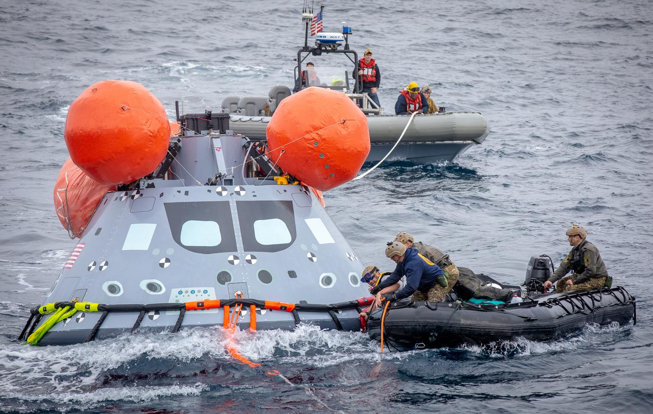 Navy divers from Explosive Ordnance Disposal (EOD) Expeditionary Support Unit 1, attach tending lines to a mock Orion capsule during Day 2 of Underway Recovery Test 9 (URT-9) aboard the USS John P. Murtha. During the weeklong test, NASA’s Landing and Recovery team is performing their final mission certification ahead of Artemis I. 