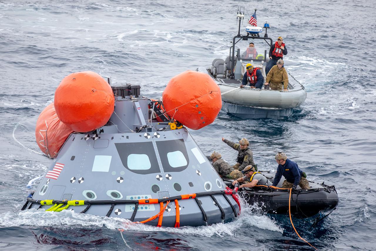 Navy divers from Explosive Ordnance Disposal (EOD) Expeditionary Support Unit 1, attach tending lines to a mock Orion capsule during Day 2 of Underway Recovery Test 9 (URT-9) aboard the USS John P. Murtha. During the weeklong test, NASA’s Landing and Recovery team is performing their final mission certification ahead of Artemis I. 