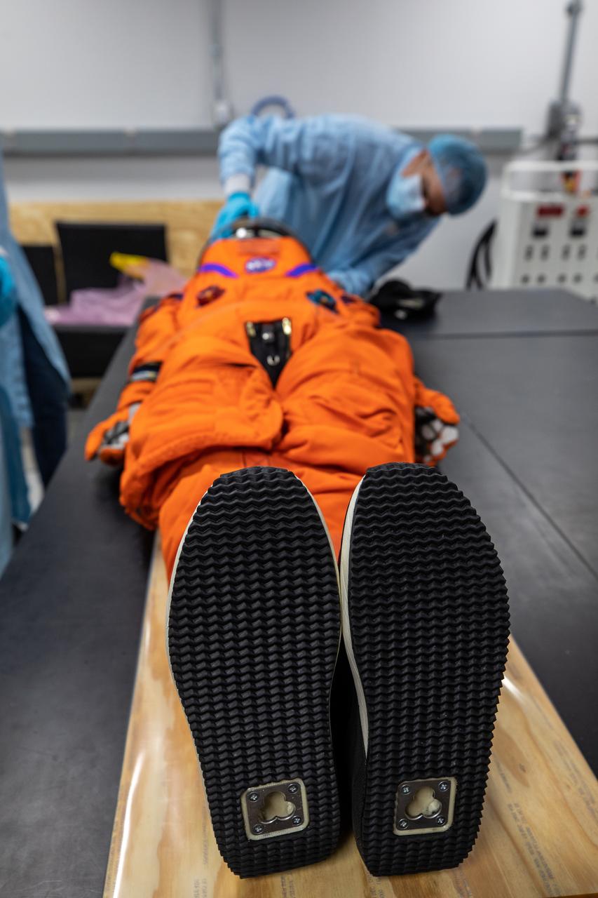 Inside the Space Station Processing Facility at NASA’s Kennedy Space Center in Florida, teams from Johnson Space Center, Exploration Ground Systems, and Jacobs TOSC conduct final inspections of Moonikin “Campos” on Nov. 9, 2021, prior to installation into the Orion crew module. Technicians checked connectivity and performed fit checks on his flight suit to ensure he is ready for flight aboard the Artemis flight test. Artemis I will be an uncrewed test flight of the Orion spacecraft and Space Launch System rocket as an integrated system ahead of crewed flights to the Moon. Under Artemis, NASA aims to land the first woman and first person of color on the Moon and establish sustainable lunar exploration. 