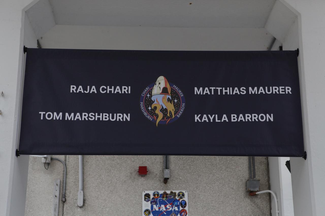 The SpaceX Crew-3 astronaut names and mission insignia are on a banner in the Astronaut Crew Quarters inside the Neil Armstrong Operations and Checkout Building at NASA’s Kennedy Space Center in Florida on launch day, Nov. 10, 2021. NASA astronauts Raja Chari, commander; Tom Marshburn, pilot; Kayla Barron, mission specialist; and Matthias Maurer, ESA (European Space Agency) astronaut and mission specialist, will launch in Crew Dragon Endurance atop the SpaceX Falcon 9 rocket to the International Space Station for NASA’s Commercial Crew Program. Crew-3 is scheduled to launch at 9:03 p.m. EST from Launch Complex 39A at Kennedy. 
