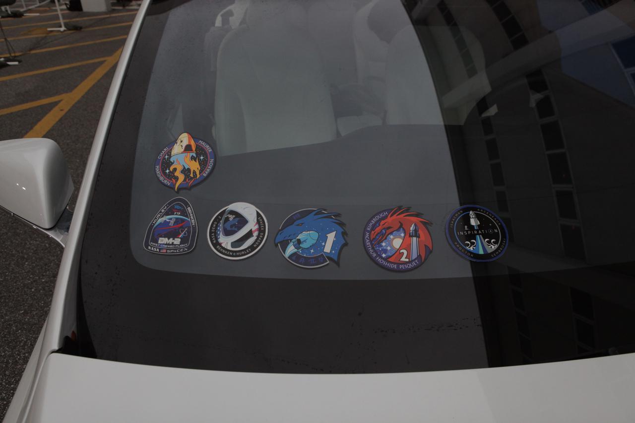 The SpaceX Crew-3 mission insignia is in view in the upper left on the windshield of a SpaceX Tesla Model X car outside the Neil Armstrong Operations and Checkout Building at NASA’s Kennedy Space Center in Florida on launch day, Nov. 10, 2021. NASA astronauts Raja Chari, commander; Tom Marshburn, pilot; Kayla Barron, mission specialist; and Matthias Maurer, ESA (European Space Agency) astronaut and mission specialist, will launch in Crew Dragon Endurance atop the SpaceX Falcon 9 rocket to the International Space Station for NASA’s Commercial Crew Program. Crew-3 is scheduled to launch at 9:03 p.m. EST from Launch Complex 39A at Kennedy.