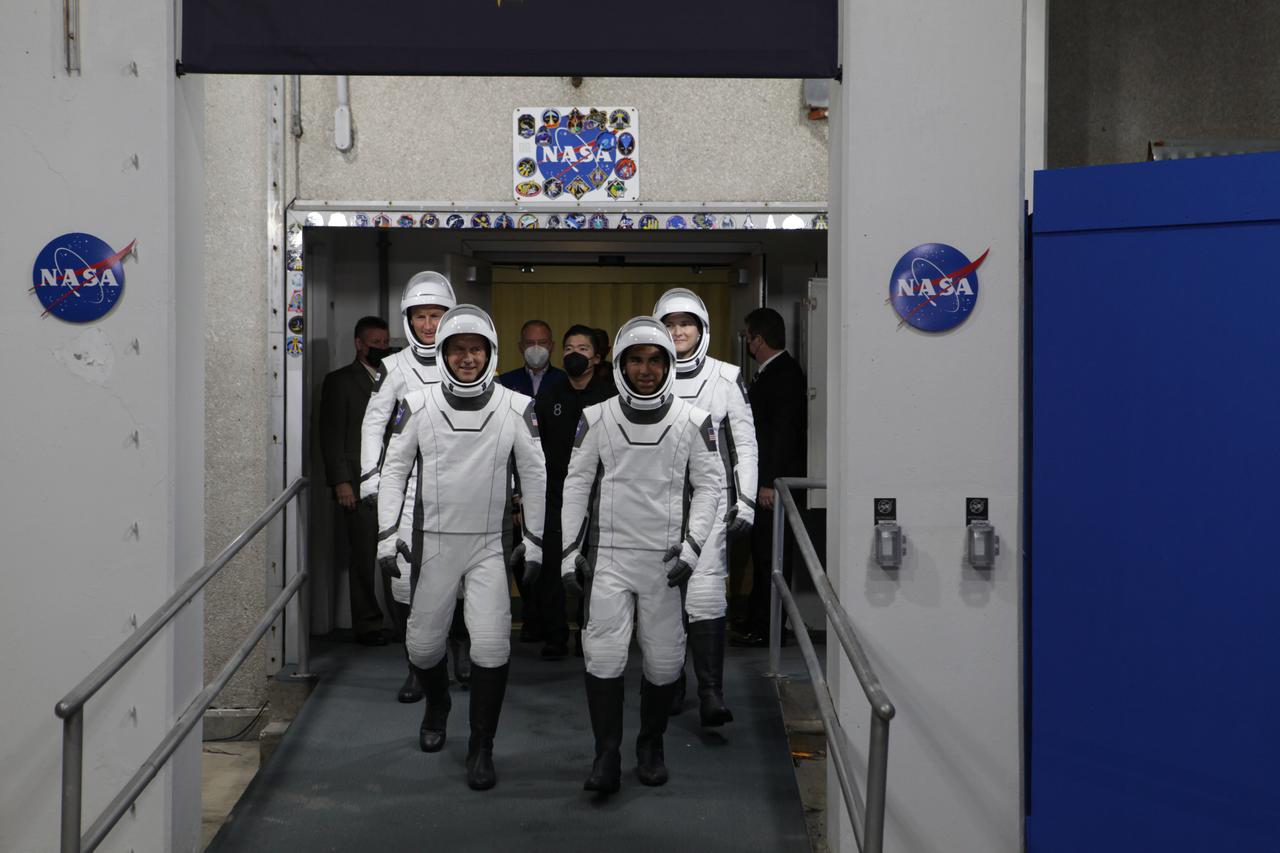 The SpaceX Crew-3 astronauts walk out through the double doors below the Neil A. Armstrong Building’s Astronaut Crew Quarters at NASA’s Kennedy Space Center in Florida on Nov. 10, 2021. They will make their way to the customized Tesla Model X cars that will take them to their spacecraft at Launch Complex 39A. In front, from left are NASA astronauts Raja Chari, commander; and Tom Marshburn, pilot. Behind them, from left are Matthias Maurer, ESA (European Space Agency astronaut) and mission specialist; and NASA astronaut Kayla Barron, mission specialist. The Falcon 9 rocket with Crew Dragon Endurance will launch the four-person crew to the International Space Station for NASA’s Commercial Crew Program. Crew-3 is scheduled to launch at 9:03 p.m. EST from Launch Complex 39A at Kennedy.