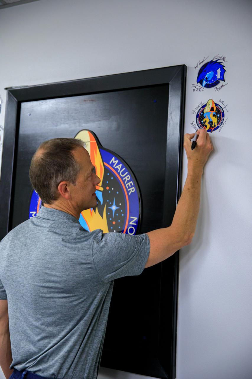 Tom Marshburn, NASA astronaut and pilot for the SpaceX Crew-3 mission, signs the mission patch on the wall in the Astronaut Crew Quarters inside the Neil Armstrong Operations and Checkout Building at NASA’s Kennedy Space Center in Florida on Nov. 10, 2021. The Falcon 9 rocket with Crew Dragon Endurance will launch the four-person crew to the International Space Station for NASA’s Commercial Crew Program. Crew-3 is scheduled to launch Nov. 10 at 9:03 p.m. EST from Launch Complex 39A at Kennedy. 