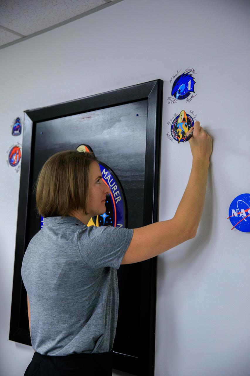 Kayla Barron, NASA astronaut and mission specialist for the SpaceX Crew-3 mission, signs the mission patch on the wall in the Astronaut Crew Quarters inside the Neil Armstrong Operations and Checkout Building at NASA’s Kennedy Space Center in Florida on Nov. 10, 2021. The Falcon 9 rocket with Crew Dragon Endurance will launch the four-person crew to the International Space Station for NASA’s Commercial Crew Program. Crew-3 is scheduled to launch Nov. 10 at 9:03 p.m. EST from Launch Complex 39A at Kennedy. 