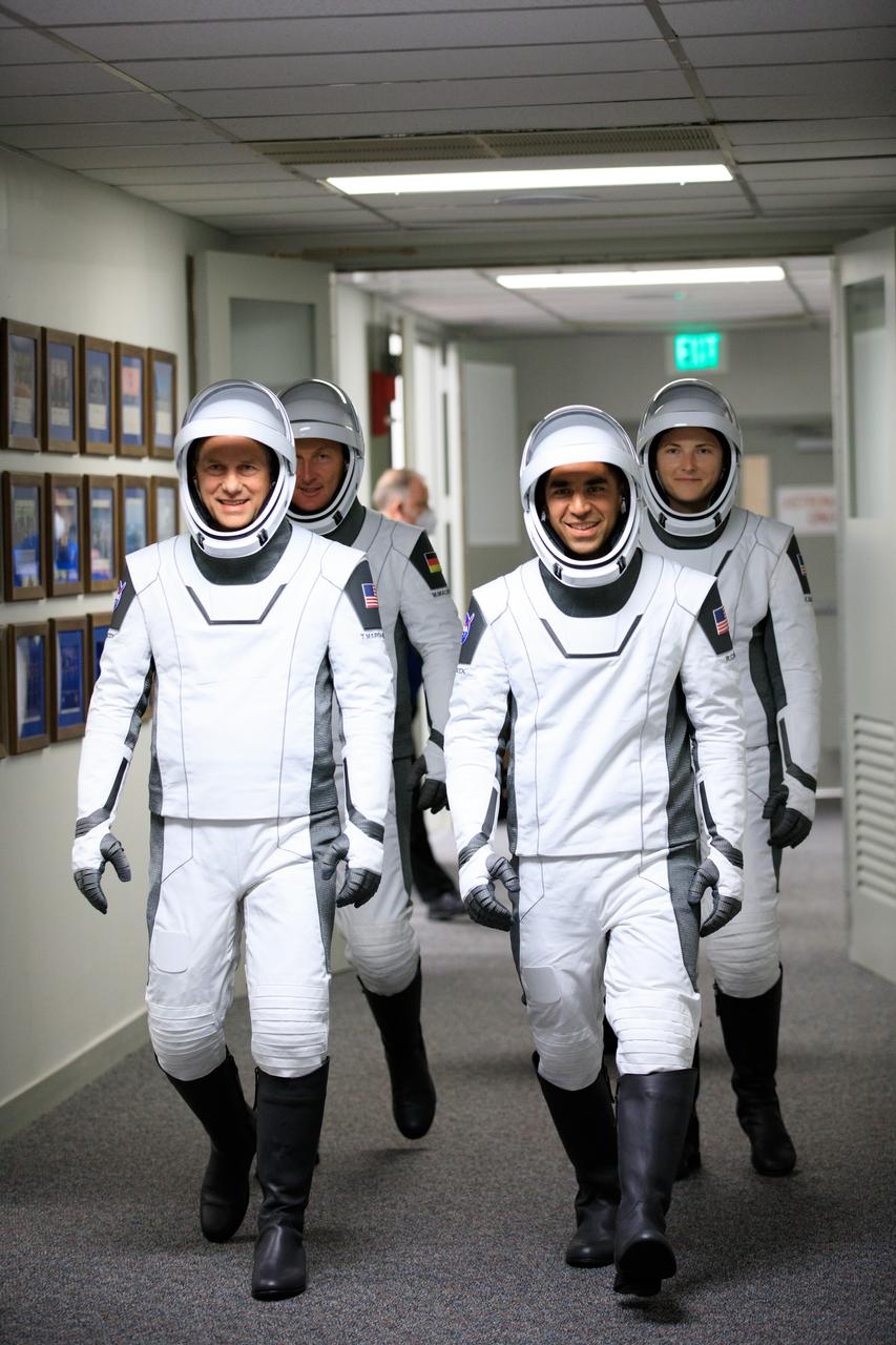 The SpaceX Crew-3 astronauts walk through the hallway in the Neil A. Armstrong Building’s Astronaut Crew Quarters at NASA’s Kennedy Space Center in Florida on Nov. 10, 2021. They will make their way to the customized Tesla Model X cars that will take them to their spacecraft at Launch Complex 39A. In front, from left are NASA astronauts Tom Marshburn, pilot, and Raja Chari, commander. Behind them, from left are Matthias Maurer, ESA (European Space Agency astronaut) and mission specialist; and NASA astronaut Kayla Barron, mission specialist. The Falcon 9 rocket with Crew Dragon Endurance will launch the four-person crew to the International Space Station for NASA’s Commercial Crew Program. Crew-3 is scheduled to launch at 9:03 p.m. EST from Launch Complex 39A at Kennedy.
