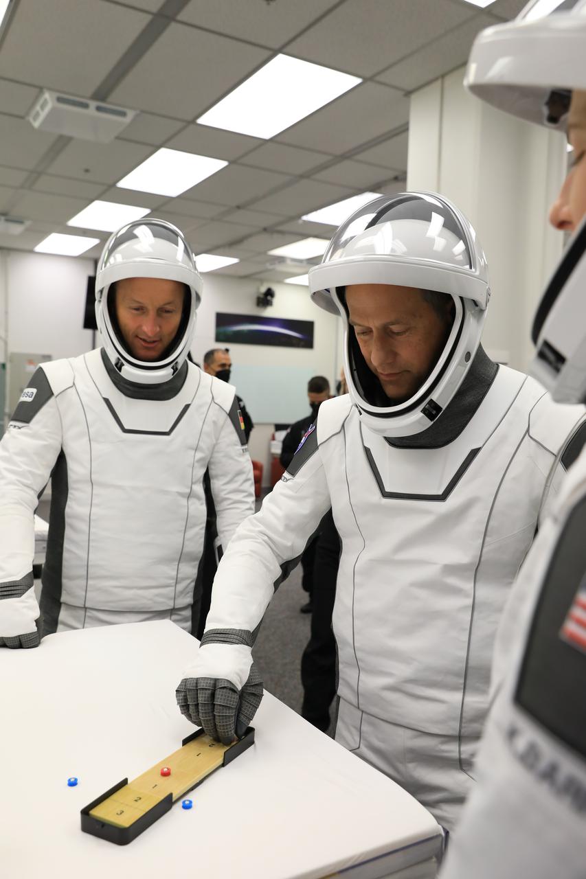 NASA SpaceX Crew-3 mission astronauts play a game while inside the suit-up room in the Astronaut Crew Quarters at Kennedy Space Center’s Neil A. Armstrong Operations and Checkout Building on launch day, Nov. 10, 2021. The Falcon 9 rocket with Crew Dragon Endurance will launch Crew-3 astronauts Raja Chari, Thomas Marshburn, Kayla Barron and Matthias Maurer to the International Space Station for NASA’s Commercial Crew Program. Crew-3 is scheduled to launch at 9:03 p.m. EST from Launch Complex 39A at Kennedy.