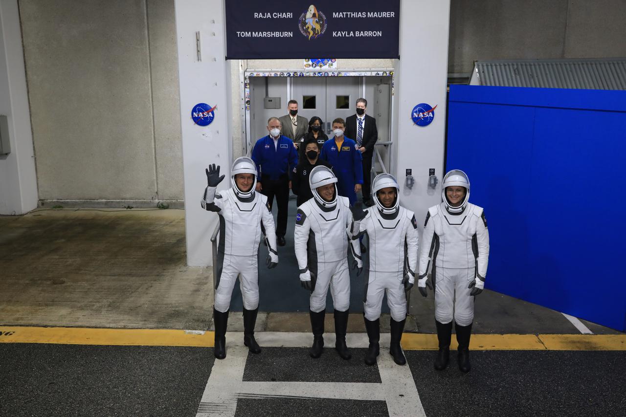 The SpaceX Crew-3 astronauts wave to family and friends after walking out through the double doors below the Neil A. Armstrong Building’s Astronaut Crew Quarters at NASA’s Kennedy Space Center in Florida on launch day, Nov. 10, 2021. They will make their way to the customized Tesla Model X cars that will take them to their spacecraft at Launch Complex 39A. From left are Matthias Maurer, ESA (European Space Agency) astronaut and mission specialist, and NASA astronauts Tom Marshburn; pilot; Raja Chari, commander; and Kayla Barron, mission specialist. The Falcon 9 rocket with Crew Dragon Endurance will launch the four-person crew to the International Space Station for NASA’s Commercial Crew Program. Crew-3 is scheduled to launch at 9:03 p.m. EST from Launch Complex 39A at Kennedy.