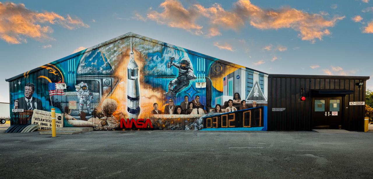 A mural painted by Florida artist Christopher Maslow adorns the northwest exterior wall of the Press Site News Facility at NASA’s Kennedy Space Center in Florida on Jan. 10, 2022. Completed by the artist over the course of several months during 2021, the largescale artwork depicts notable landmarks, missions, and milestones from the history of NASA and its world-famous spaceport. The Press Site News Facility is the hub of launch broadcasts and home to the center’s TV auditorium. Along with the nearby NASA News Center, for decades Kennedy’s Press Site has been where reporters from television, radio, print, and online media outlets have monitored countless launches, landings, and other space events in order to deliver the news to the world. 