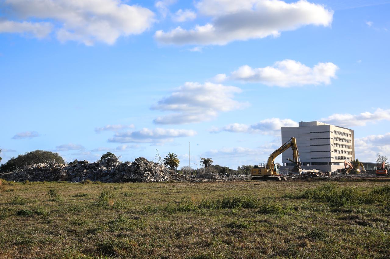 In the foreground is remnants of the former headquarters building at NASA’s Kennedy Space Center on Jan. 11, 2022. Built in 1965, the 439,000-square-foot structure was demolished and replaced at the Florida spaceport by the 200,000-square-foot, seven-story Central Campus Headquarters (CCHQ) Building, shown in the background. The CCHQ is a modernized, energy efficient facility representative of Kennedy’s transformation to America’s premier multi-user spaceport. It opened in May 2019. The area previously occupied by the old headquarters building will be utilized as greenspace.