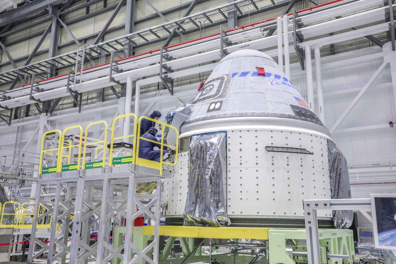 Starliner technicians work on the Orbital Flight Test-2 spacecraft in the high bay of Boeing’s Commercial Crew and Cargo Processing Facility at NASA’s Kennedy Space Center in Florida on Jan. 13, 2022.