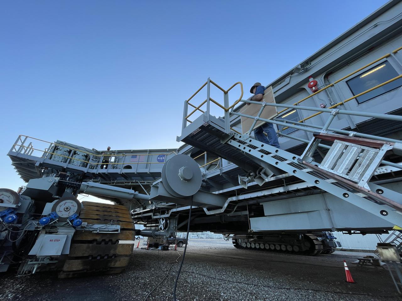 Graphic Artist Kim Keller carries up the eight new NASA Artemis logos (four large, four small) for installation on Crawler-Transporter 2 at Kennedy Space Center in Florida. The new logos were installed in preparation for the upcoming launch of Artemis I. Named after the twin sister of Apollo, Artemis is the Goddess of the Moon. The Artemis missions will take humanity back to the Moon and beyond, beginning a new legacy of deep space exploration.